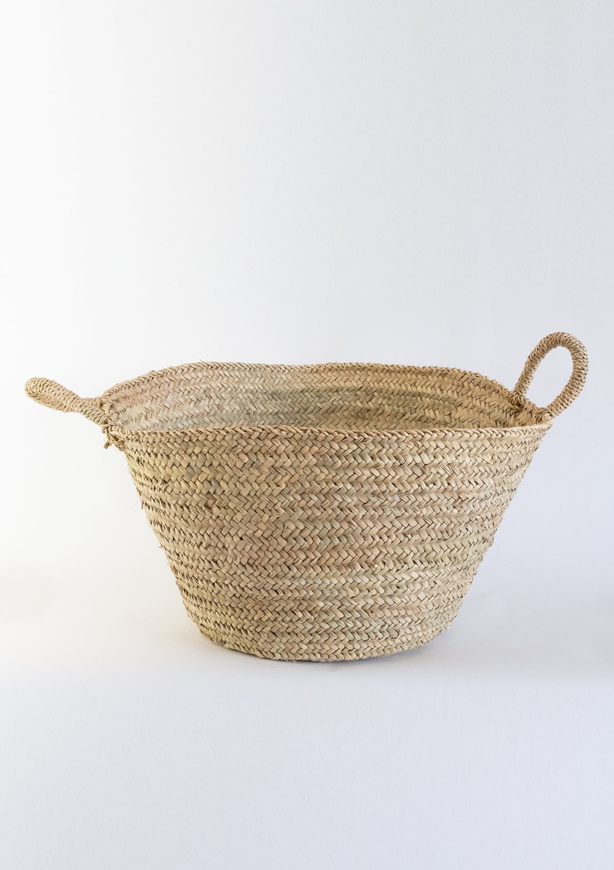 The Almazan basket is made from hand woven palm leaves and has two handles.